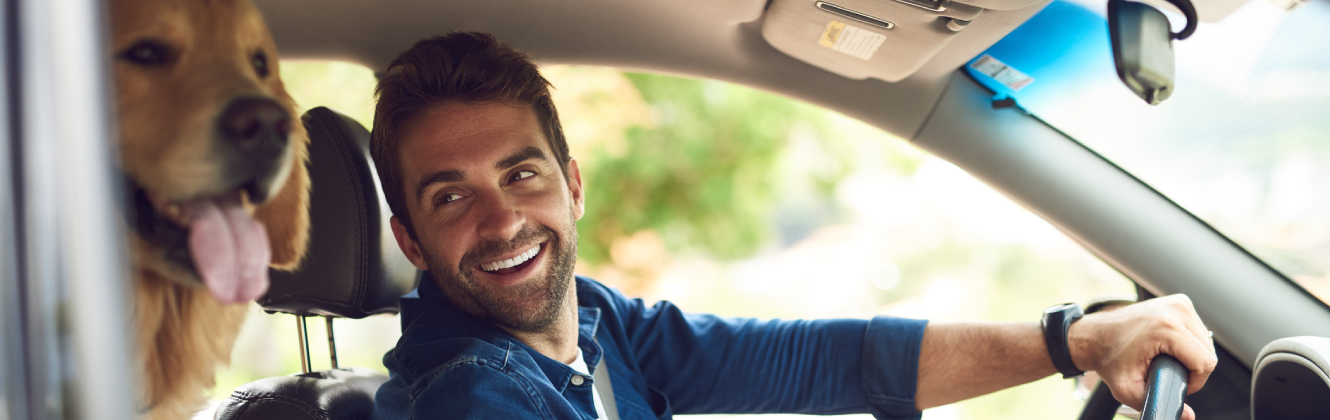 a man smiling at dog in car